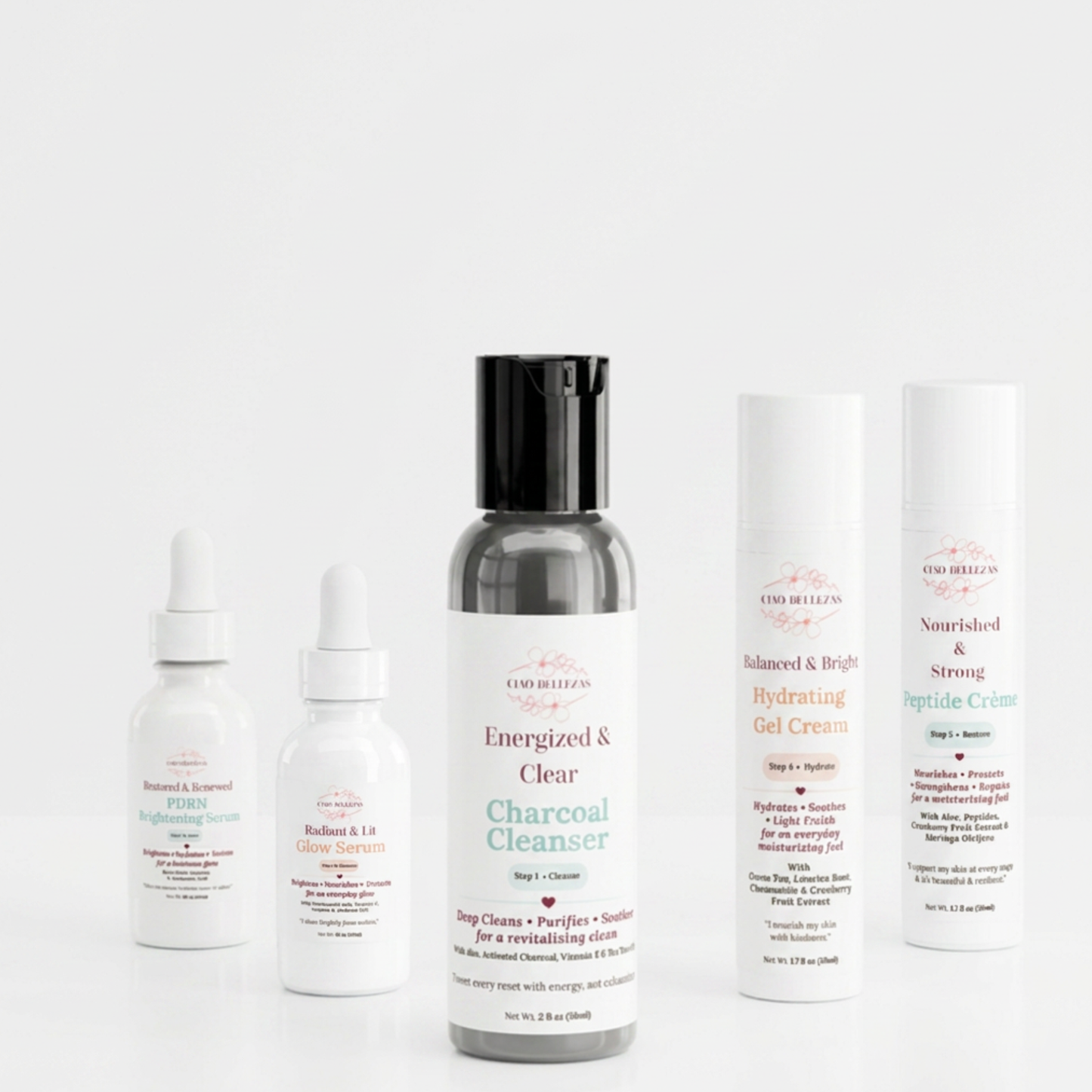 A three-piece build your own  skincare set from Good Healers of Nashville arranged on a seamless white background. The set includes a charcoal cleanser in a dark gray bottle with a black cap, a brightening serum in a white dropper bottle, a glow serum in a white dropper bottle, a hydrating gel cream in a white tube, and a strong peptide cream in a white tube.